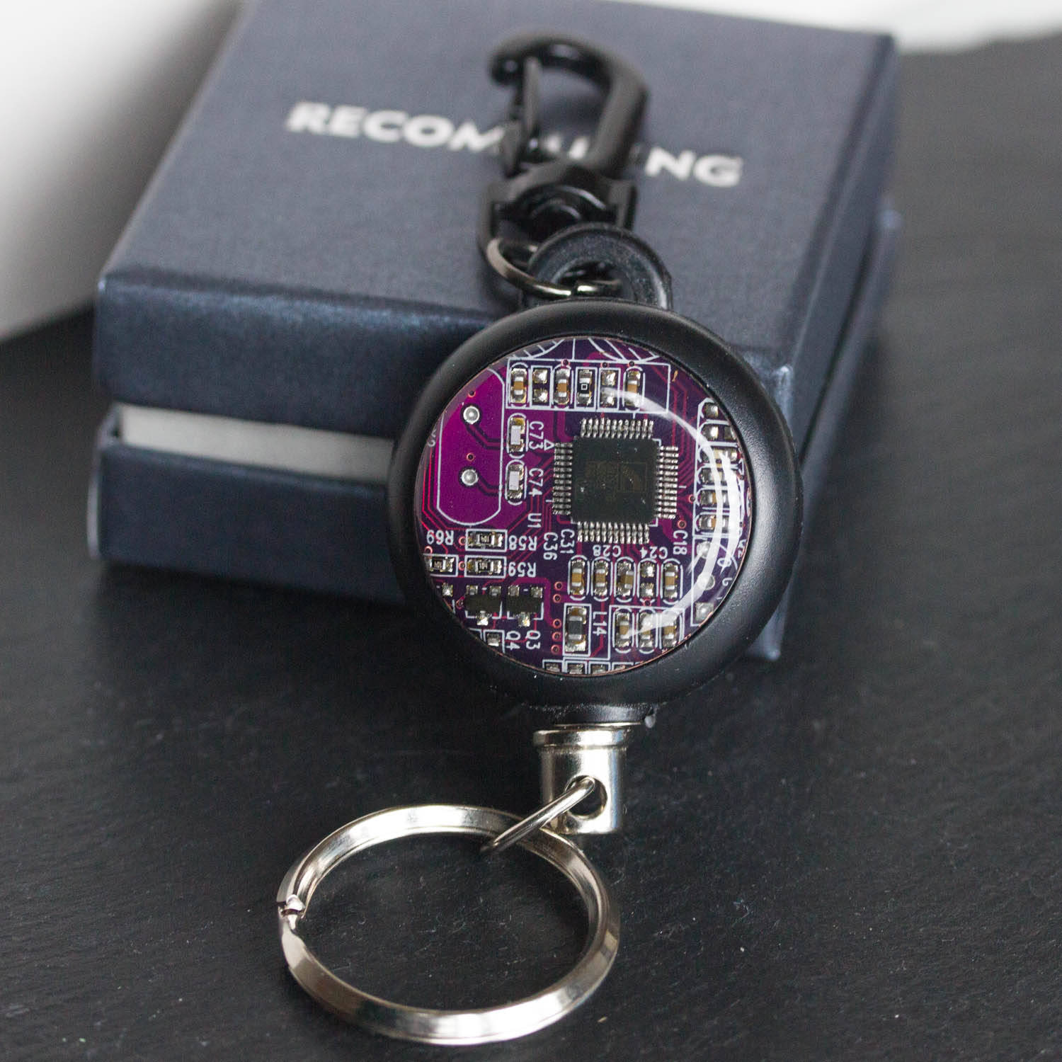 Retractable badge holder with a circuit board piece