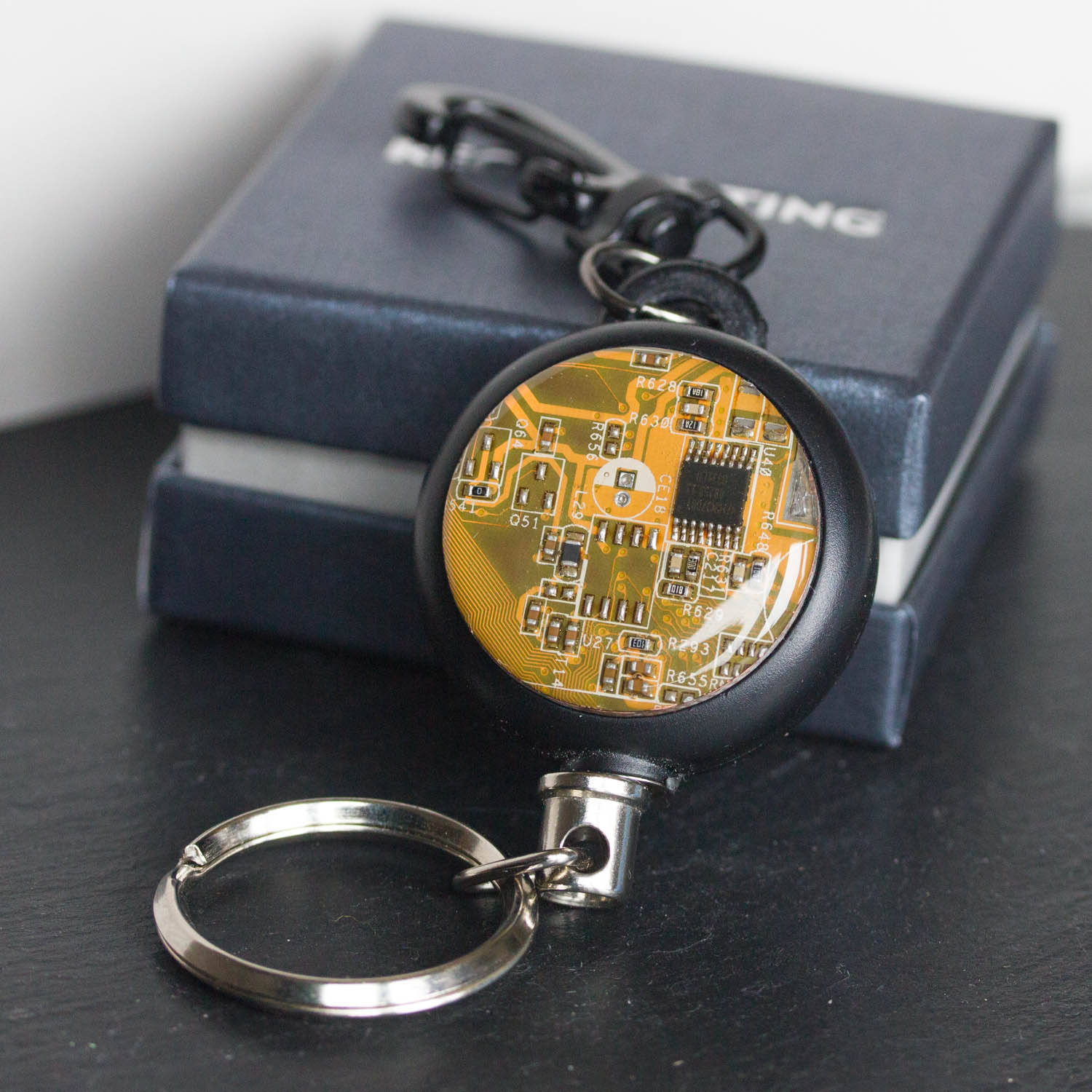 Retractable badge holder with a circuit board piece